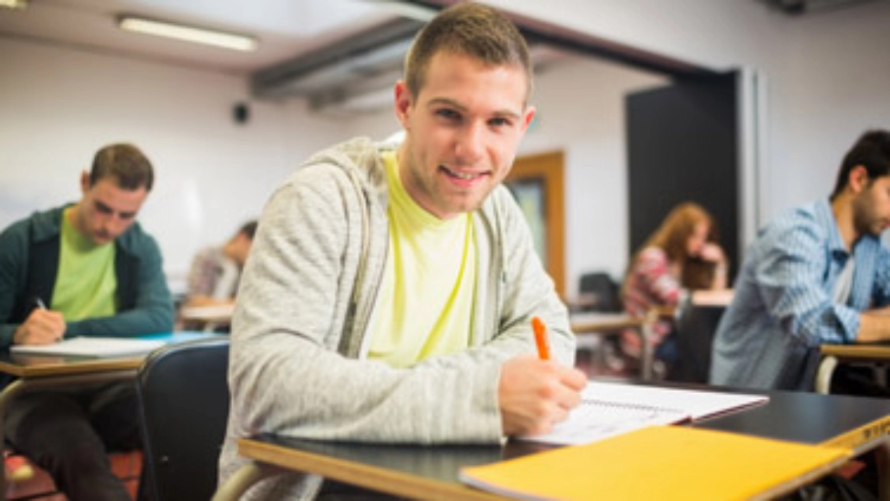 Student sitzt an einem Tisch im Seminarraum und macht sich Notizen.