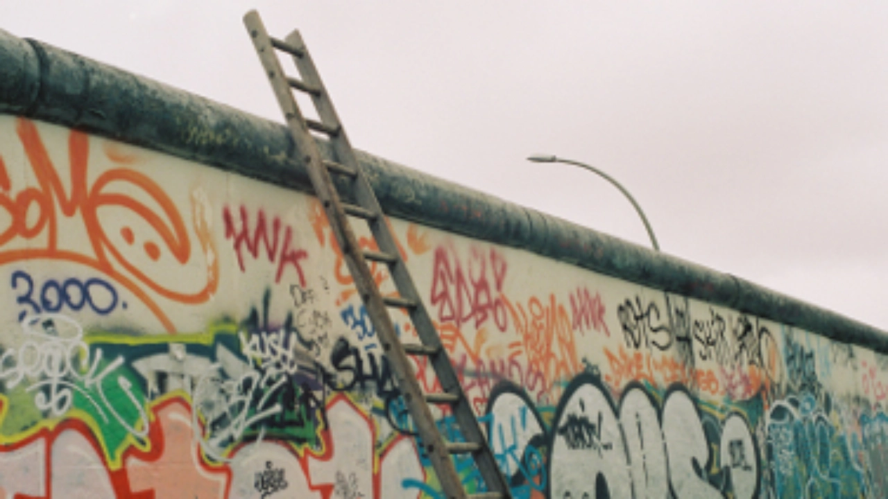 Eine Leiter lehnt an der Berliner Mauer.