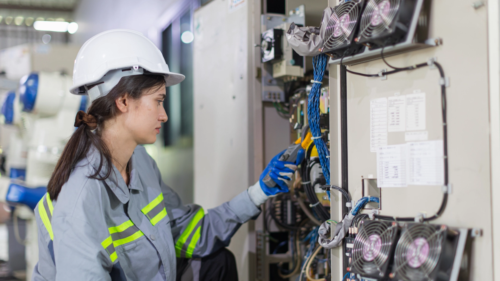 Elektronikerin prüft die Spannung an einem Schaltschrank.