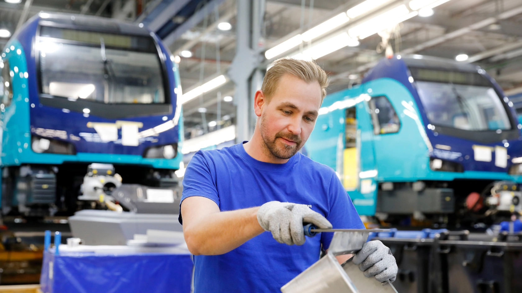 Ein Mitarbeiter feilt ein Metallteil beim Hersteller von Schienenfahrzeugen Stadler in Berlin