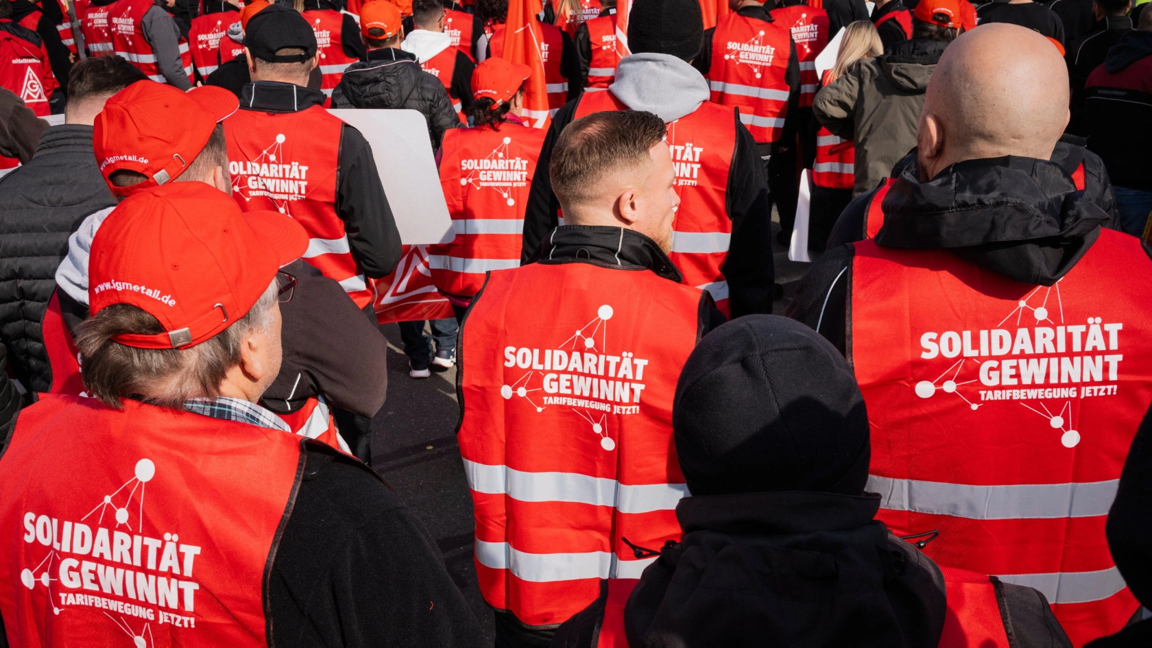 Beschäftigte tragen rote Westen mit dem Aufdruck „Solidarität gewinnt. Tarifbewegung jetzt“ auf dem Rücken