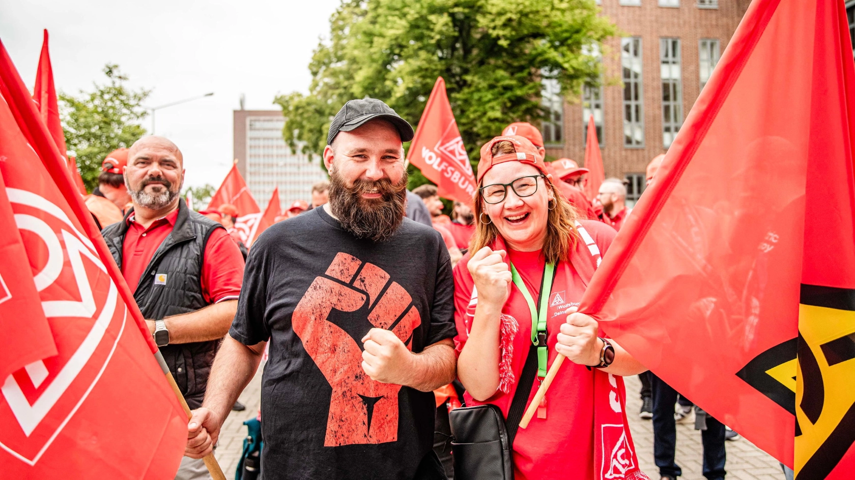 Ein Mann und eine Frau mit IG Metall-Fahnen beim Automobil-Aktionstag bei VW am 09.07.2026 in Wolfsburg