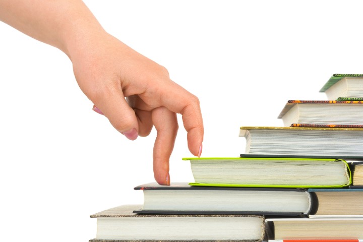 Hand läuft symbolisch eine Büchertreppe hinauf